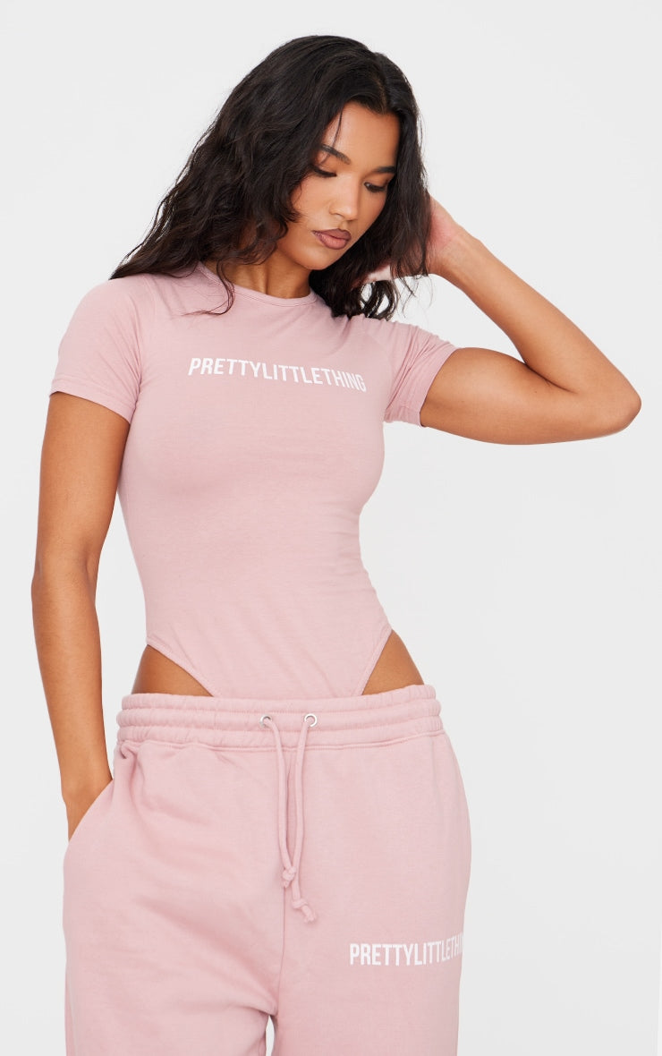 https://cdn-img.prettylittlething.com/1/9/a/b/19ab25477dd2c33dd82ebd4a17a68cb9754964ba_CNF2379_1_prettylittlething_light_pink_logo_short_sleeve_bodysuit.jpg